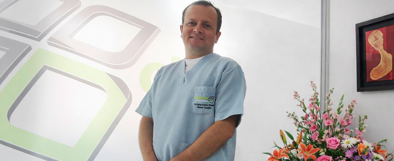 Dr Rafale Obando en Dientes & Sonrisa Bogotá en la sala de espera decorada con flores y el logo en el vidrio